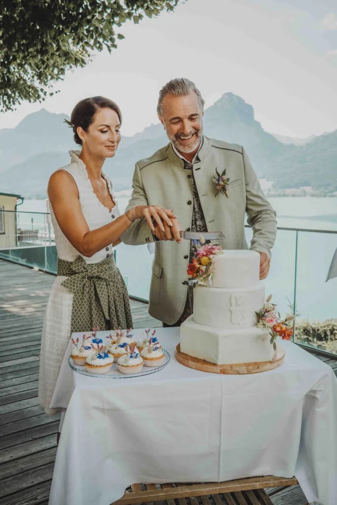 Hochzeit Feier. Paar schneidet Hochzeitstorte an. Mit Blick auf den Wolfgangsee.