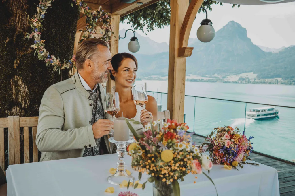 Hochzeit Paar mit zweit Gläsern in der Hand. Blick auf den Wolfgangsee.